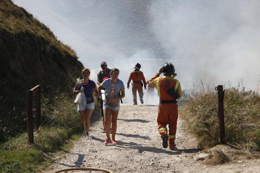Los bañistas son desalojados de la playa mientras los bomberos tratan de apagar el incendio en Torimbia - Nel Acebal (El Comercio)